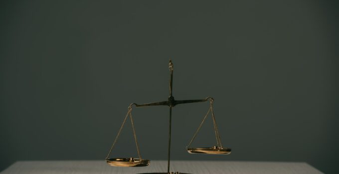 empty scales of justice on wooden table on grey